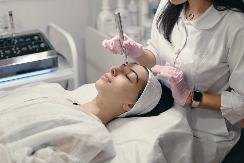 kobieta z ręcznikiem na głowie relaksuje się podczas medycyny estetycznej na twarz